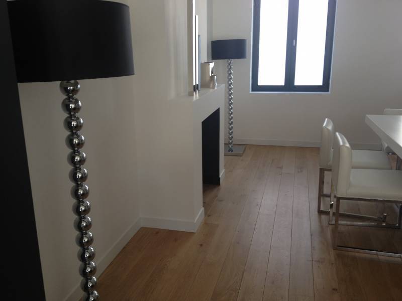Intérieur moderne lumineux avec parquet clair. Deux lampadaires design à boules argentées, cheminée blanche, fenêtre et table à manger.