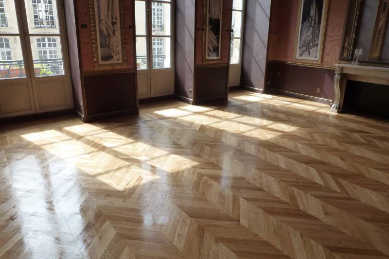 Pièce vide élégante avec parquet chevron clair brillant et rayons de soleil traversant de hautes fenêtres sur murs rouges.