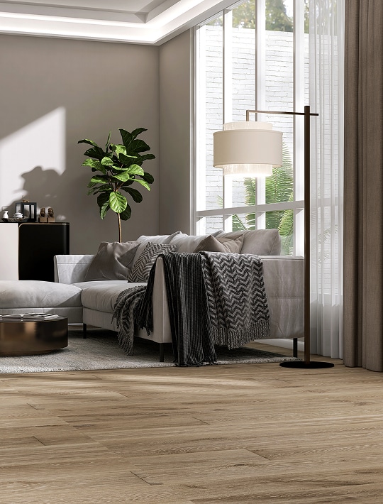 Salon moderne avec canapé gris, jeté, lampe sur pied et parquet en bois clair près d'une grande fenêtre lumineuse.
